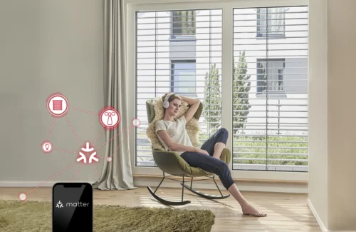 Frau entspannt im Wohnraum mit großen Fenstern und Raffstores, gesteuert über Smart Home System mit Matter-Technologie